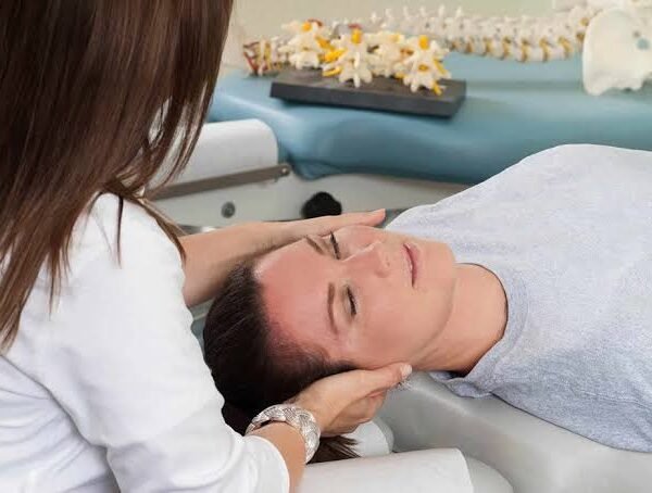 Chiropractor gently holding a patient's head and neck