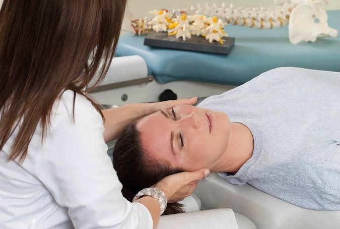 Chiropractor gently holding a patient's head and neck