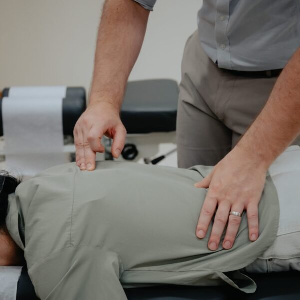 Chiropractor adjusting a patient's upper back on a treatment table