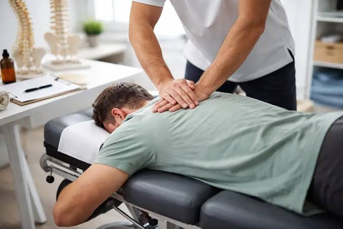 Chiropractor applying a spinal adjustment to a patient lying face down