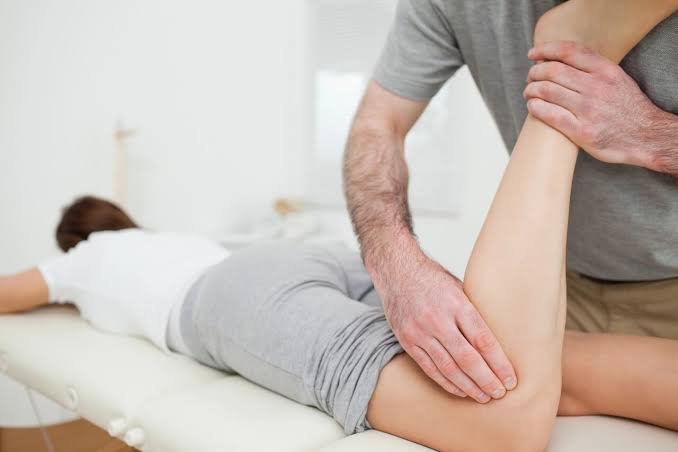 Physiotherapist stretching a patient's leg during treatment